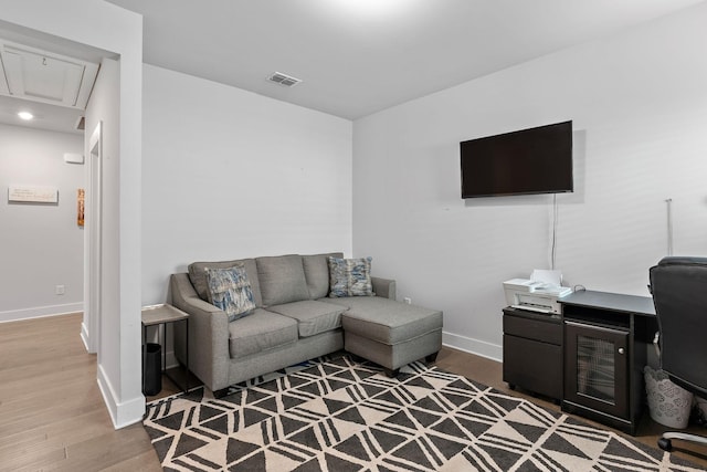 living room with baseboards, wood finished floors, visible vents, and attic access