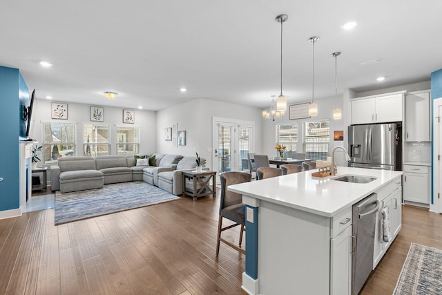 kitchen with a kitchen island with sink, white cabinetry, light countertops, and open floor plan