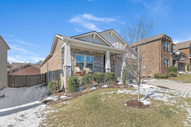 view of front of home with a garage, stone siding, covered porch, fence, and board and batten siding