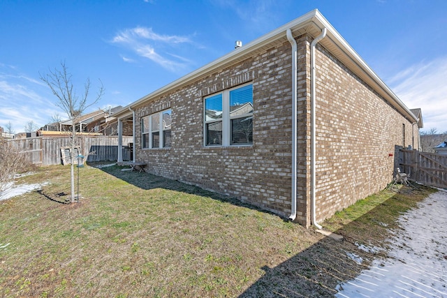 view of home's exterior with brick siding, fence, and a lawn