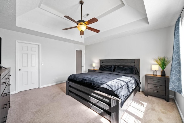 bedroom featuring baseboards, a raised ceiling, visible vents, and light colored carpet