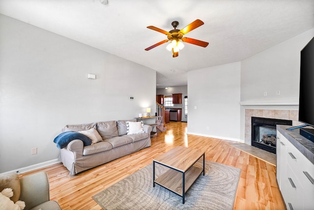 living room with baseboards, a fireplace, stairway, and light wood finished floors