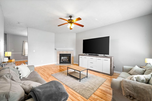 living room featuring ceiling fan, light wood-type flooring, and baseboards