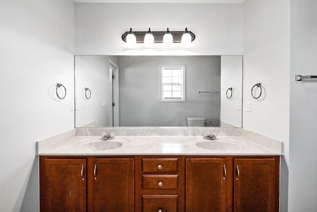 full bathroom with double vanity, a sink, and toilet