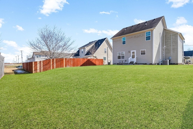 back of property with central air condition unit, fence, and a yard