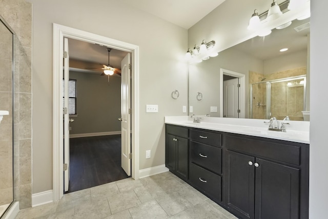 bathroom featuring double vanity, a shower stall, baseboards, and a sink