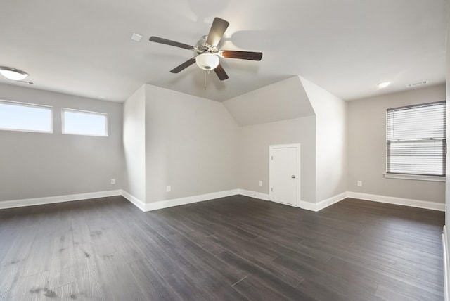 additional living space with dark wood-style floors, visible vents, ceiling fan, and baseboards