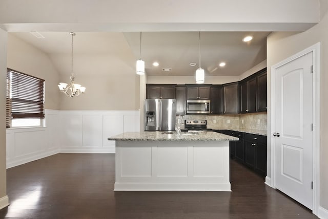 kitchen featuring light stone countertops, stainless steel appliances, decorative backsplash, a center island with sink, and pendant lighting