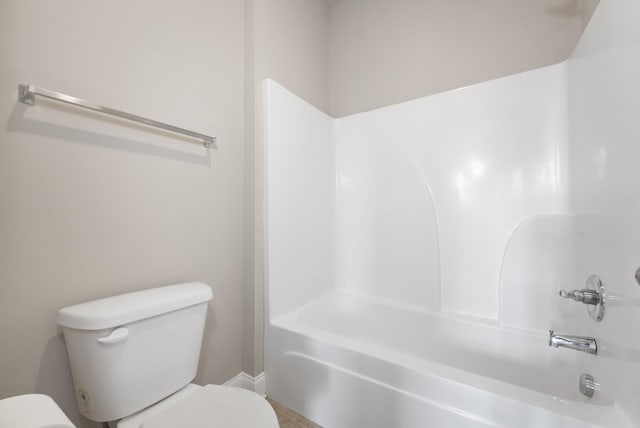 bathroom featuring shower / washtub combination, toilet, and baseboards