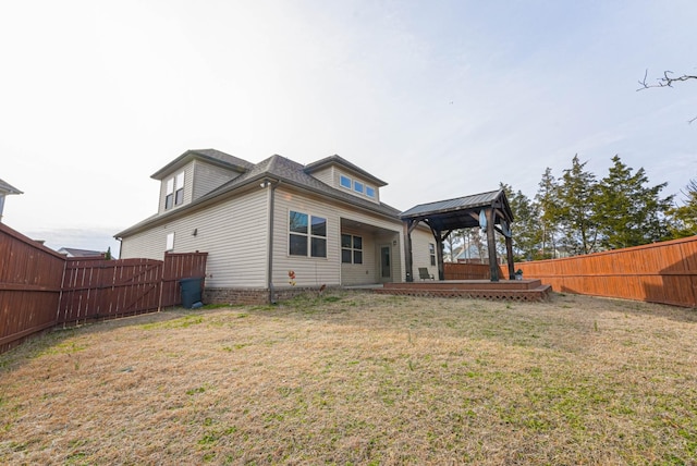 rear view of property with a fenced backyard, a yard, and a gazebo