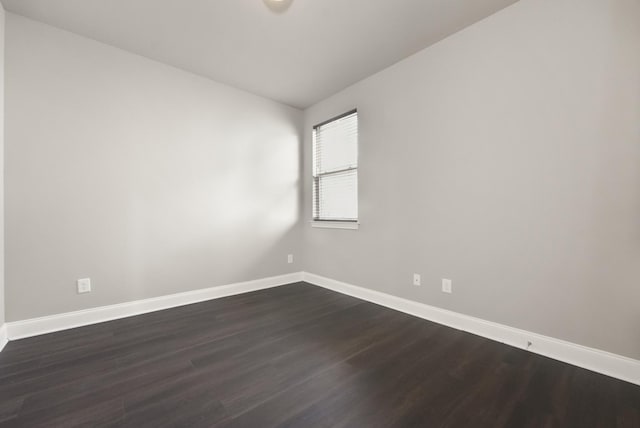 empty room featuring vaulted ceiling, baseboards, and dark wood finished floors