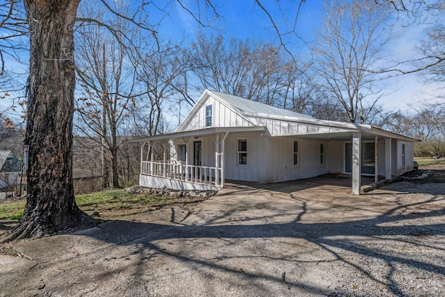 view of home's exterior with a porch, driveway, metal roof, and a carport