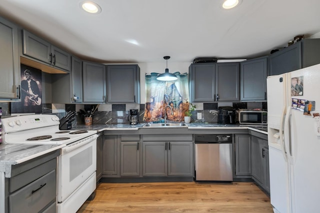 kitchen with backsplash, gray cabinetry, light wood-style flooring, white appliances, and a sink