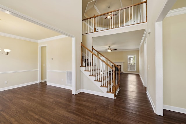 foyer with ornamental molding, stairway, dark wood finished floors, and baseboards