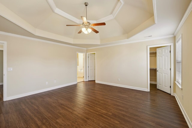 spare room with crown molding, dark wood-style flooring, a raised ceiling, and baseboards