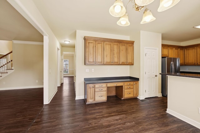 kitchen featuring dark wood-style floors, dark countertops, built in study area, and freestanding refrigerator