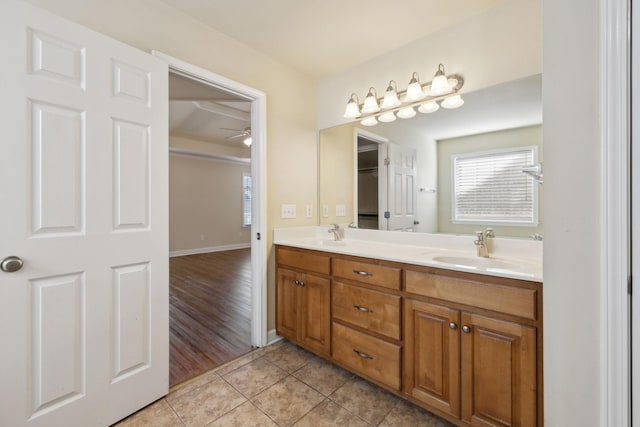 bathroom with baseboards, double vanity, a sink, and tile patterned floors