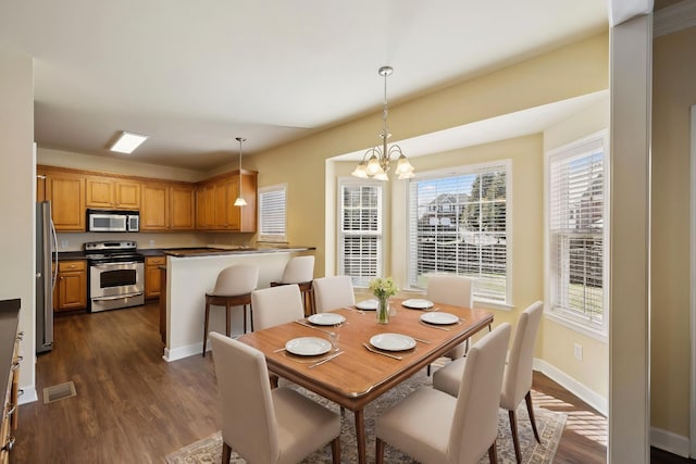 dining space featuring a chandelier, dark wood-type flooring, visible vents, and baseboards