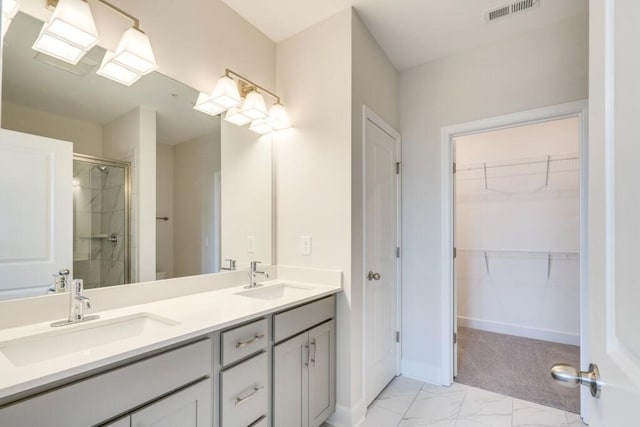 bathroom with marble finish floor, a sink, visible vents, and a walk in closet