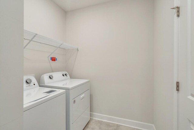 washroom with laundry area, washing machine and dryer, and baseboards