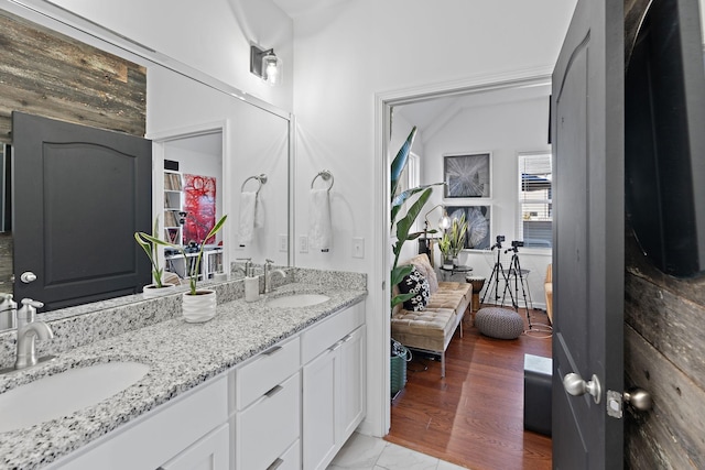 bathroom featuring double vanity, wood finished floors, and a sink