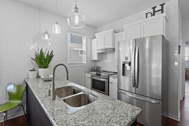 kitchen featuring under cabinet range hood, stainless steel appliances, a sink, tile walls, and white cabinets