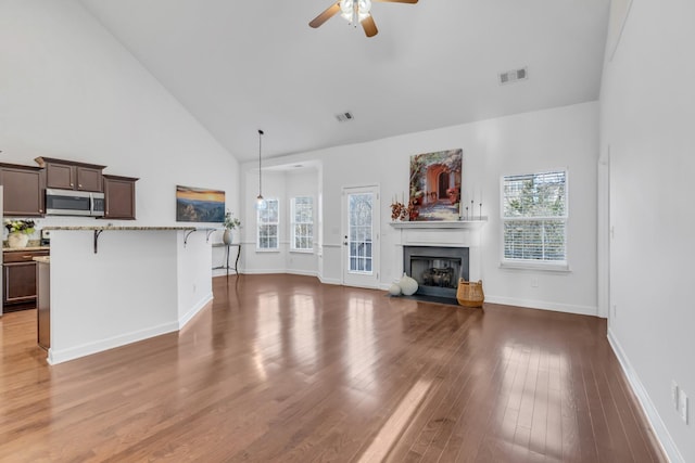 unfurnished living room with plenty of natural light, visible vents, a fireplace, and wood finished floors