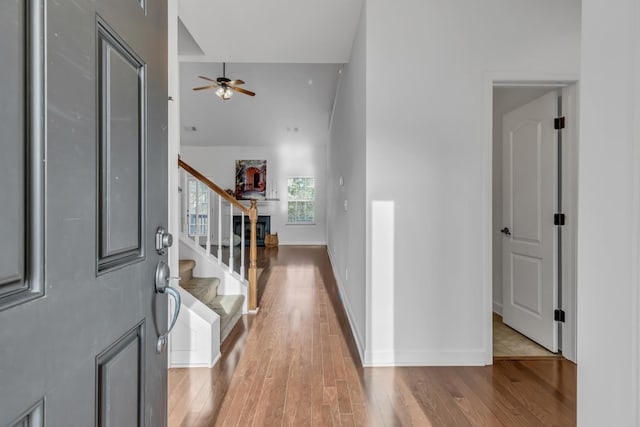 entrance foyer with stairway, a high ceiling, a ceiling fan, baseboards, and hardwood / wood-style flooring