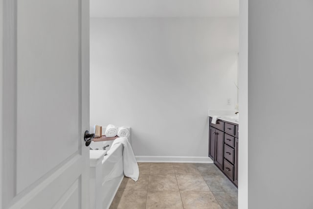 full bath featuring a garden tub, tile patterned floors, vanity, and baseboards