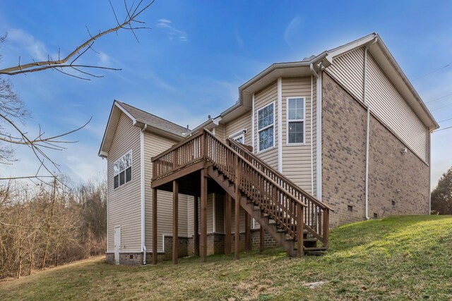 back of house featuring brick siding, a yard, stairway, crawl space, and a wooden deck