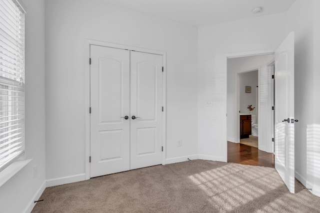 unfurnished bedroom featuring carpet floors, multiple windows, a closet, and baseboards