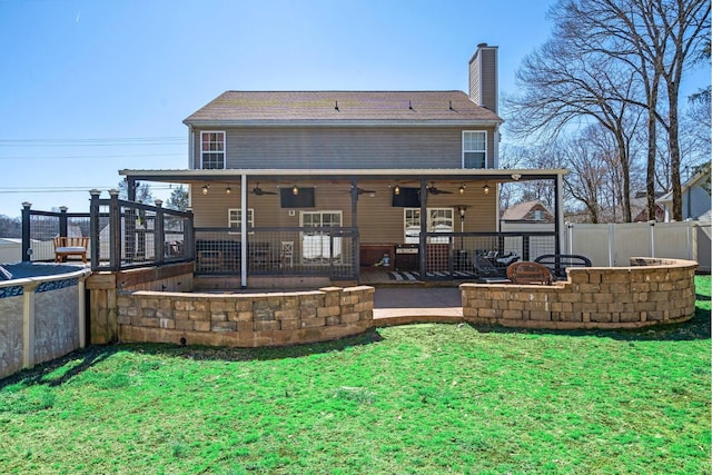 rear view of property with an outdoor fire pit, fence, a ceiling fan, a yard, and a chimney