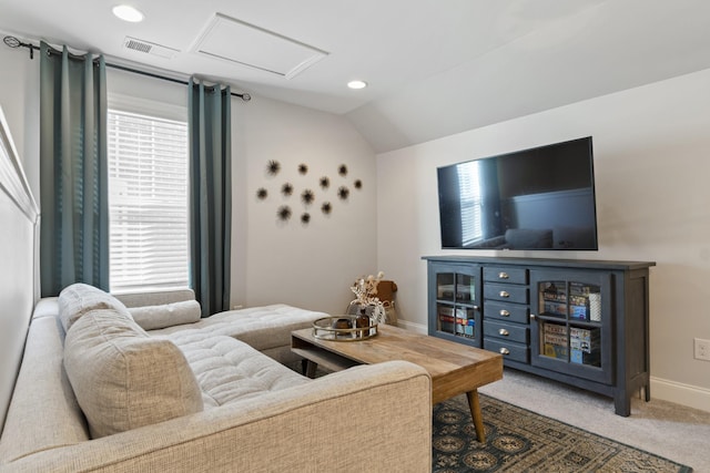 carpeted living room with attic access, visible vents, vaulted ceiling, and a wealth of natural light