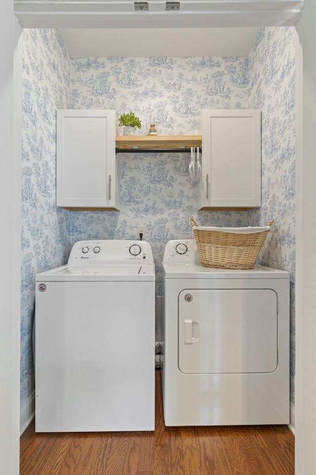 laundry area with wallpapered walls, wood finished floors, cabinet space, and independent washer and dryer