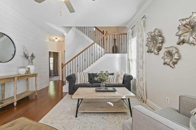 living room with dark wood finished floors, a ceiling fan, ornamental molding, baseboards, and stairs