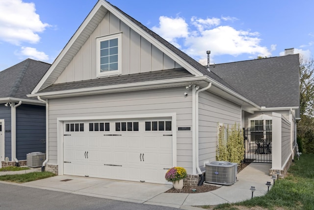 exterior space with central air condition unit, a shingled roof, and board and batten siding