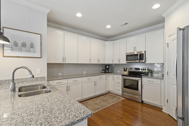 kitchen featuring light stone counters, stainless steel appliances, ornamental molding, white cabinetry, and a sink