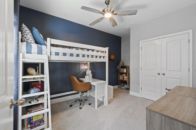 bedroom with baseboards, a ceiling fan, a closet, and light colored carpet