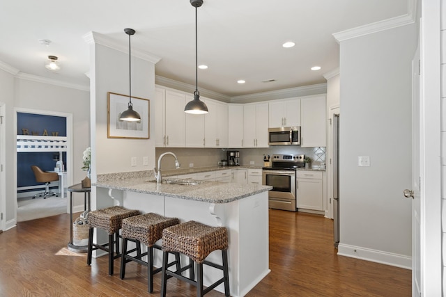 kitchen with pendant lighting, appliances with stainless steel finishes, white cabinets, a sink, and a peninsula