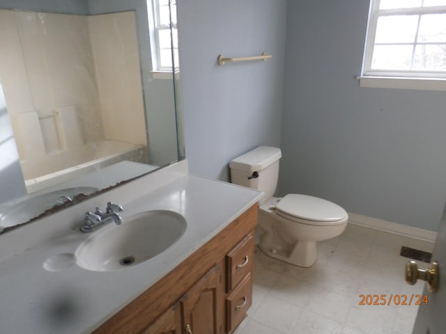 full bathroom with a healthy amount of sunlight, baseboards, toilet, and vanity