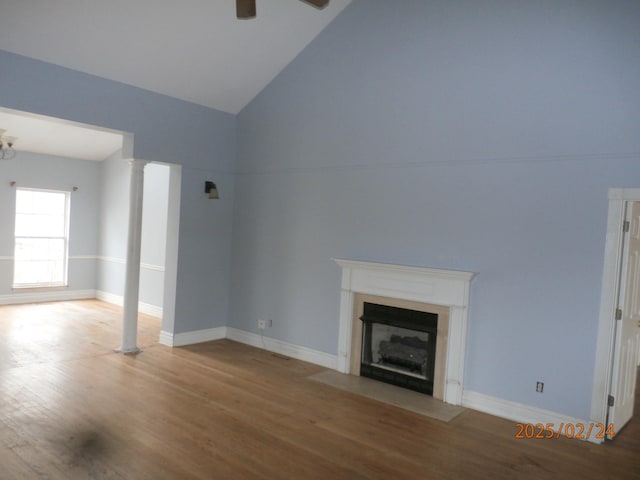 unfurnished living room with decorative columns, lofted ceiling, a fireplace with flush hearth, ceiling fan, and wood finished floors