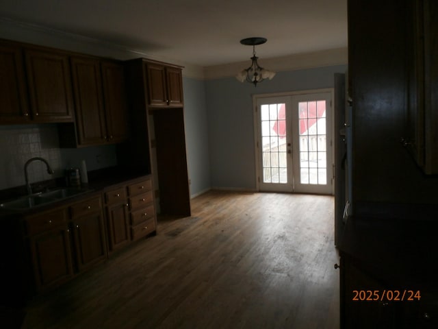 kitchen with dark countertops, wood finished floors, a sink, french doors, and backsplash