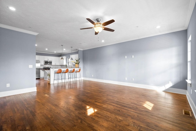 unfurnished living room with dark wood-style floors, baseboards, visible vents, and ornamental molding