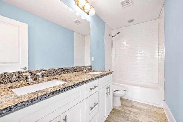 bathroom featuring toilet, a textured ceiling, visible vents, and a sink