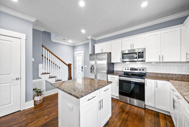 kitchen with white cabinets, dark wood finished floors, stainless steel appliances, and dark stone countertops