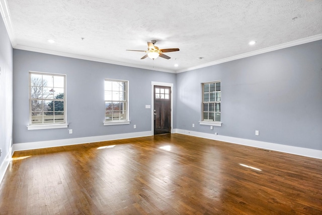 interior space with a textured ceiling, a ceiling fan, baseboards, ornamental molding, and dark wood-style floors