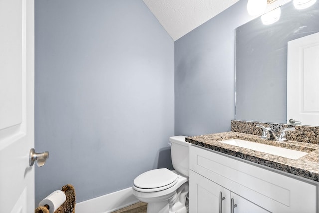 bathroom with a textured ceiling, toilet, vanity, baseboards, and vaulted ceiling