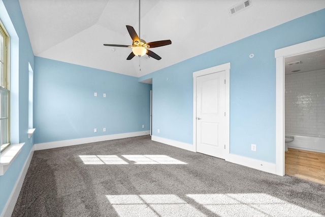 unfurnished bedroom featuring carpet, visible vents, vaulted ceiling, and baseboards