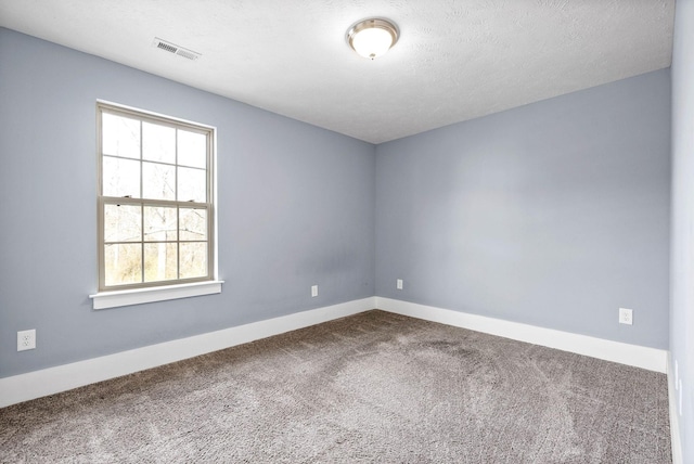 carpeted spare room with visible vents, a textured ceiling, and baseboards