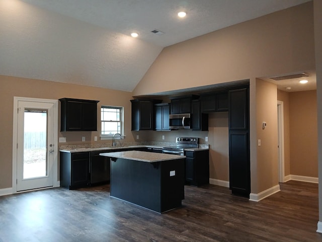 kitchen featuring baseboards, appliances with stainless steel finishes, dark wood-type flooring, and a center island